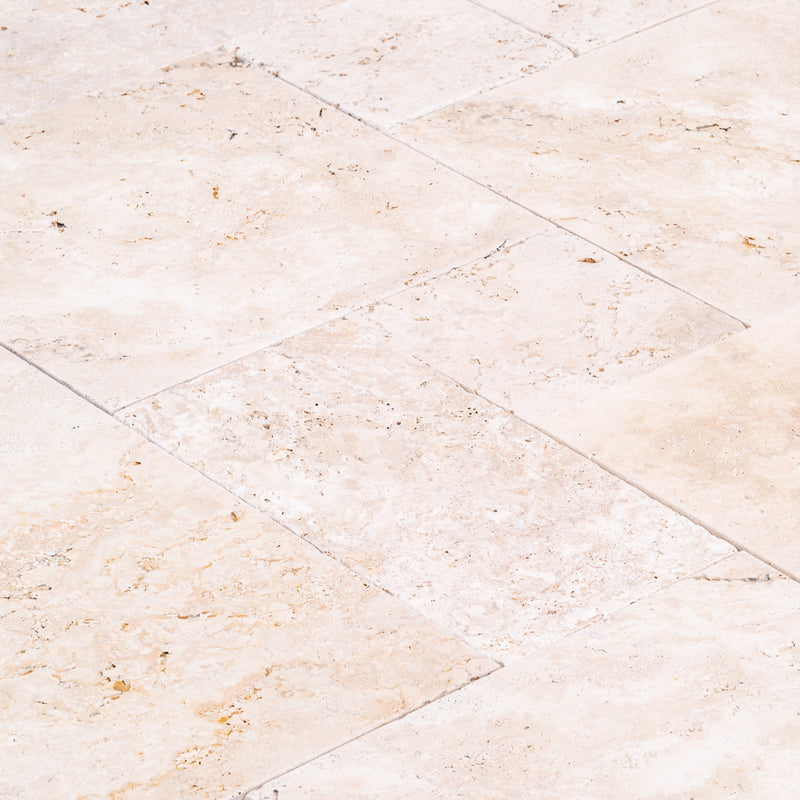 Light antique travertine pavers unfilled tumbled pattern angle closeup view