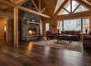 Cozy living room in a log cabin with a fireplace, couches, and large windows.