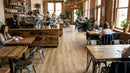 Interior of a cozy coffee shop with wooden tables and chairs, and patrons enjoying their time.