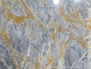 Close-up of marble with gray and gold veining, brand 'GRISS' visible.
