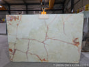 Green onyx slab with red vein patterns in a warehouse setting