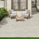 Outdoor patio with wooden chairs, table, and cushions on a stone patio.