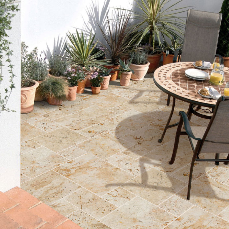 Light antique travertine pavers unfilled tumbled pattern installed on patio floor plants round table chairs