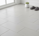 White tiled floor with a herringbone pattern in a room with a window and a small plant.