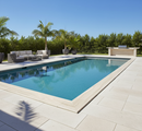 Rectangular pool with lounge area and outdoor furniture on a sunny day.