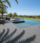 Modern outdoor pool area with lounge chairs, palm trees, and a clear blue sky.