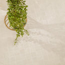 Beige square mosaic floor tiles with a subtle embossed pattern, styled with a green trailing plant in a gold wire basket.