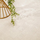 Off-white square ceramic tiles with a subtle textured finish, styled with a gold wire plant stand and a trailing green eucalyptus vine.