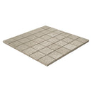 A square mosaic tile sheet made of small light beige stone or concrete-look tiles with a speckled texture, shown at an angle on a plain white background.