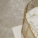 Gray square tile flooring shown from an overhead angle, with a gold wire basket and white textured rug partially visible in the foreground.