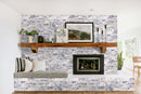 New York Ledger 3D Panel 6"x24" Natural Marble Wall Tile - Full Truckload installed around fireplace wooden mantel setting corder pillows and a scenery painting on the wall
