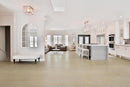 Modern open-plan living room and kitchen with white walls and wooden flooring. Dawn