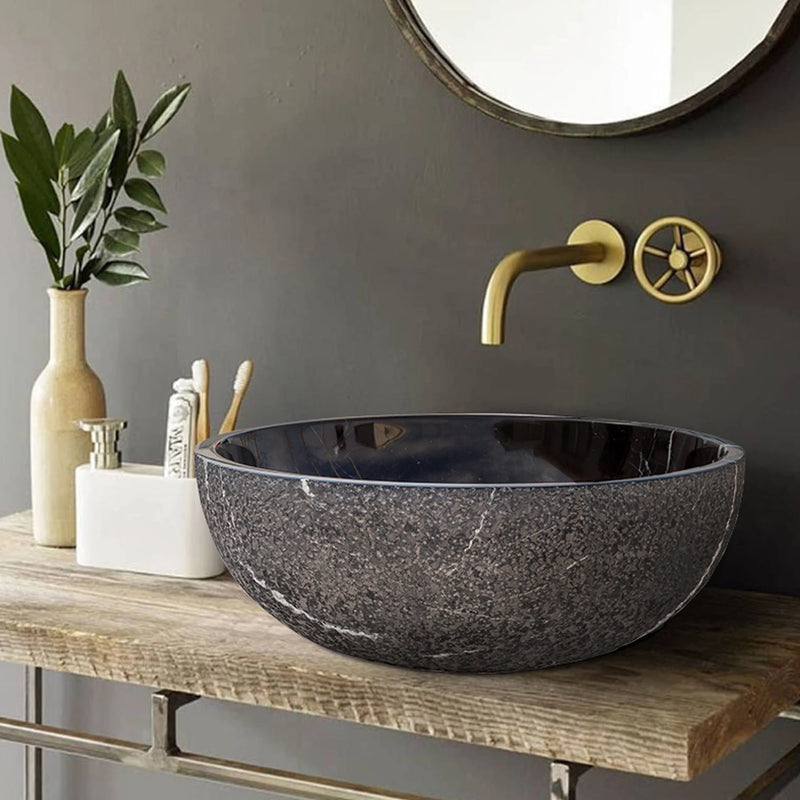 Toros Black Marble Above-Vanity Bathroom Vessel Sink Rough Exterior (D)16" (H)6" installed above wooden vanity with metal frames gold color faucet and toothbrushes and toothpaste bathroom set with beige color vase and green flowers
