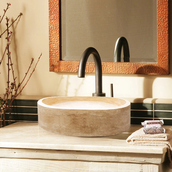 Troia Light Travertine Cylinder Round Above Vanity Bathroom Sink Honed (D)16" (H)6" installed above marble vanity black faucet and copper rectangular wall mirror and beige towels on the vanity