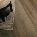 Wooden floor with a rug and a chair corner.