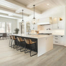 Modern kitchen with white island, stools, and pendant lights.