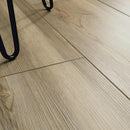 Close-up of wooden floor tiles with a black metal chair leg in the corner.