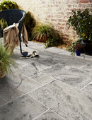 Alaska Silver Travertine Pattern Tumbled Pavers - Full Truckload patio view with magazines on floor and wooden chair towel on top plants wide view