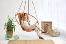 bresse rast blue hanging round chair frame woman sitting green vases decorative throw blanket wicker rug on floor angle