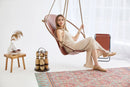 brown genuine leather hanging round chair teak frame blonde woman sitting magazine holder angle view