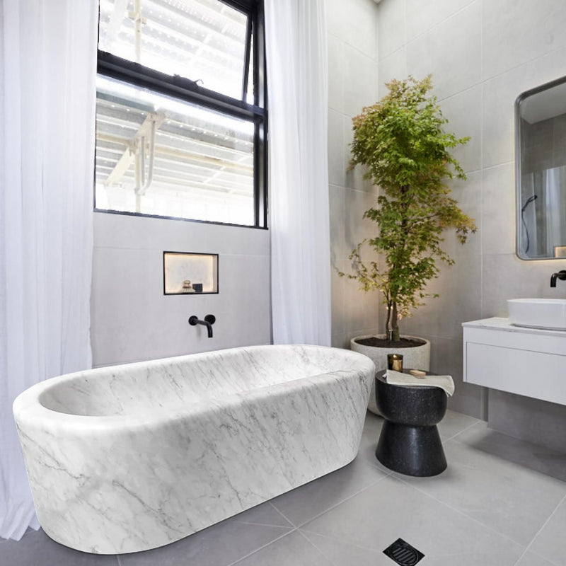 Imperial White Marble Bathtub Hand-carved from Solid Marble Block (W)32" (L)70" (H)20"installed high ceiling bathroom big black windows and a tree inside a big vase gray ceramic floors