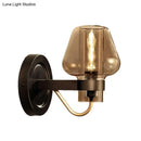 Modern black and brass wall sconce with amber glass bedroom light