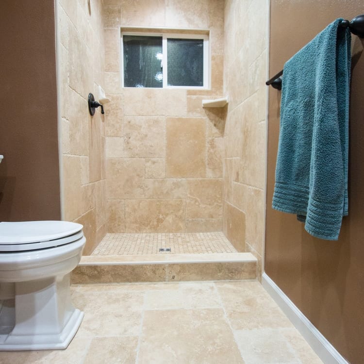 Denizli Beige Antique Pattern Travertine Tile - Full Truckload brushed and chiseled installed bathroom wall and floor blow hand towel hung on the right hand side