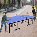 Two people playing ping pong on an outdoor table with a park-like setting.