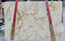 Marble slab with beige and brown veins on a red and brown support structure.