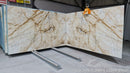 Marble slabs with gold veining on a metal stand, likely in a warehouse setting.