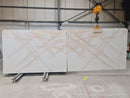 Two large marble slabs with a beige and white pattern on a warehouse floor.