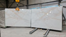 Large white marble slabs with gold veining in a warehouse setting.