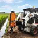 Skid steer loader with a soil auger attachment near a water body.