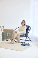 indigo foldable metal frame faux leather chair black metal frame product shot decorative items around woman sitting