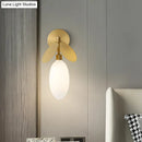 Modern brass leaf wall lamp with cream glass bedroom sconce