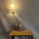 Modern brass led wall sconce with white fabric shade for bedroom
