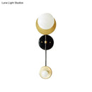 Modern gold and black wall sconce with opal glass shade bedroom light