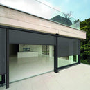 Modern house with large glass doors and windows, surrounded by greenery.