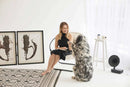 off white foldable metal frame faux leather chair black frame black dressed woman sitting on it dog and white side table and 2 picture frames