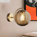 Postmodern brass armed ball sconce – bedroom amber glass wall light