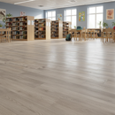 Spacious classroom with wooden flooring, bookshelves, and tables.