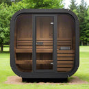 Portable outdoor sauna with wooden interior and black exterior on a grassy area with trees in the background.