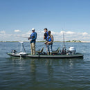 Three people on a boat fishing in a calm body of water with a clear sky.