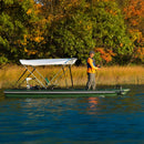 Person fishing on a pontoon boat on a lake with autumn foliage in the background