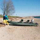 Person pushing an inflatable boat on a sandy beach with a clear sky.