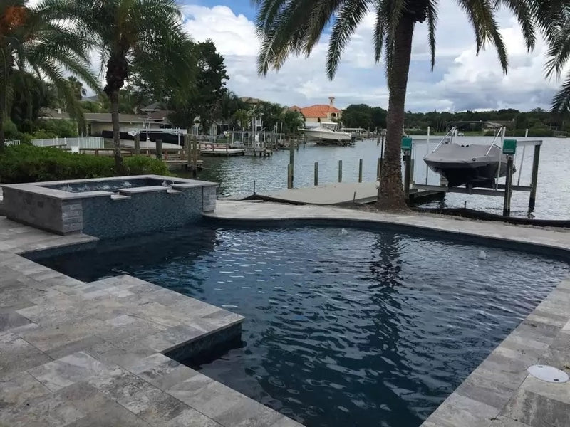 silver travertine pavers tumbled pattern installed around pool Miami wide view