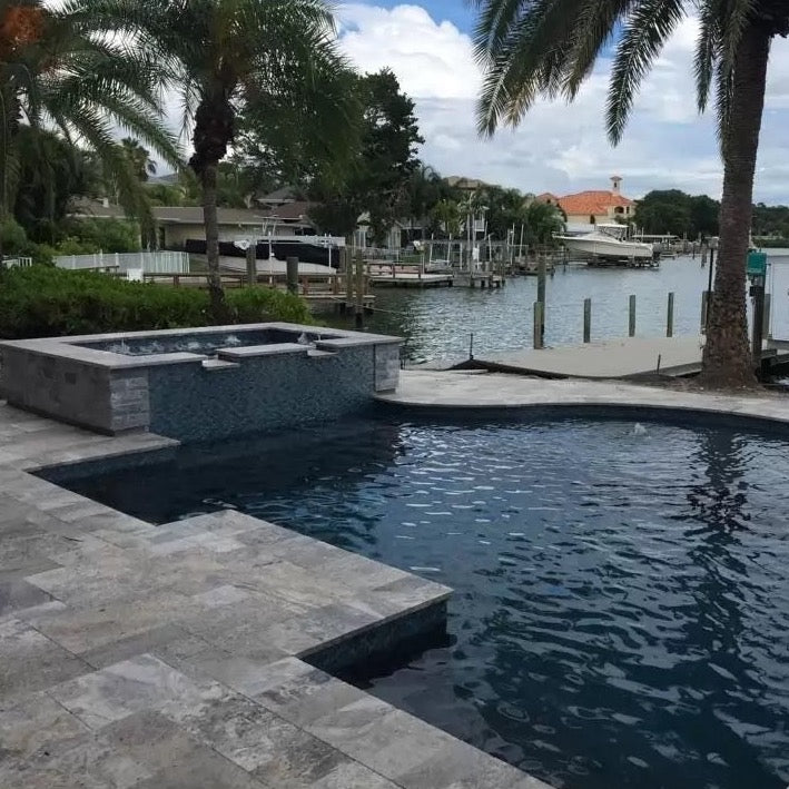 silver travertine pavers tumbled pattern installed around pool Miami view