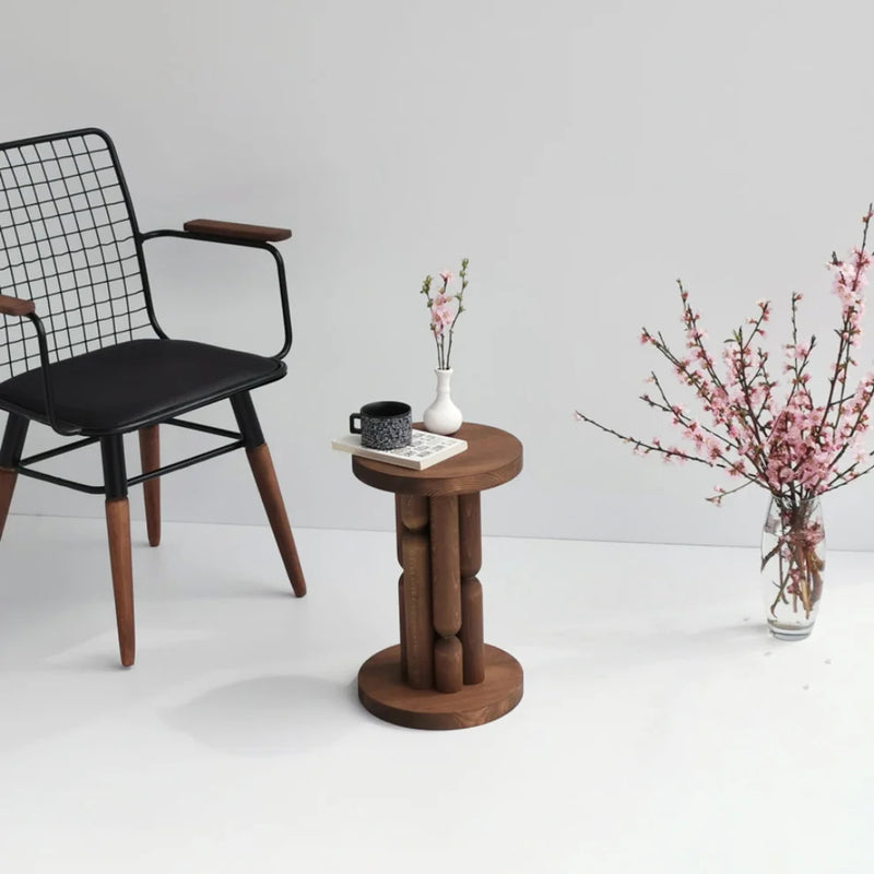 Stoa Designer Side Table Solid Wood Beech (W)10.5" (L)10.5" (H)16.5"  next to modern black chair book and some decorative items on top