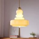 Tiered yellow glass pendant lights with brass accents for kitchens