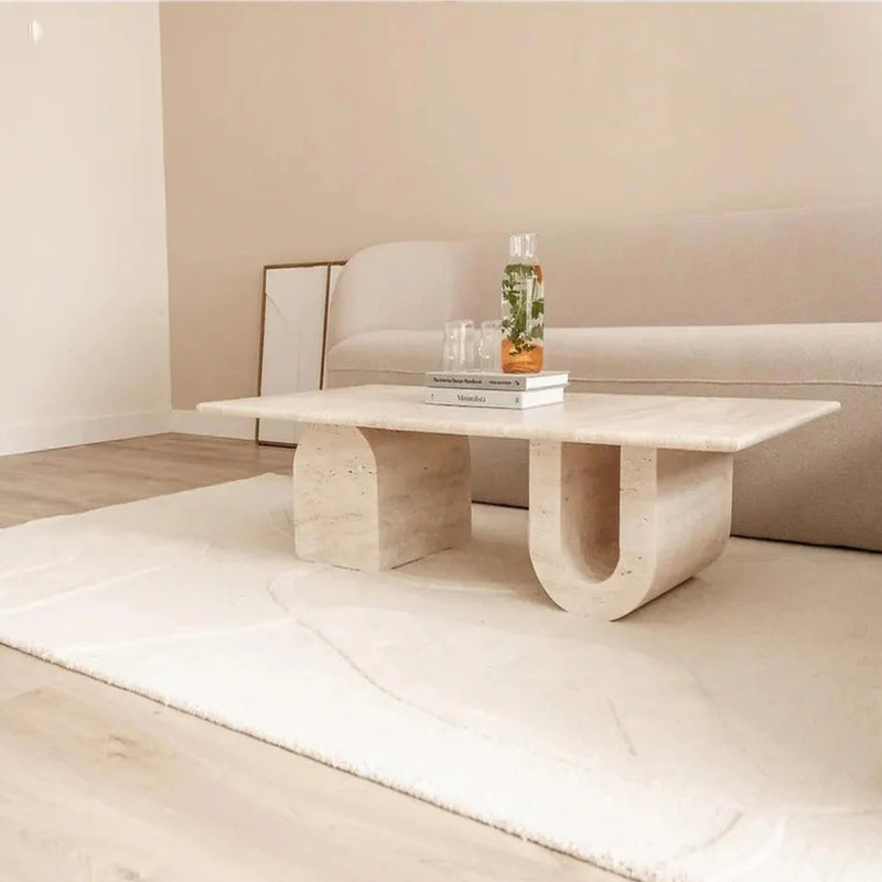 Troia Light Travertine Designer Coffee Table U Shape Legs (W)28" (L)48" (H)13" installed living room white area rug on floor beige walls magazines on the coffee table spa water inside glass bottle and 2 glasses